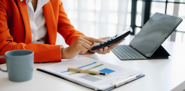 Businesswoman hands working with finances about cost and calculator and laptop with tablet smartphone at office