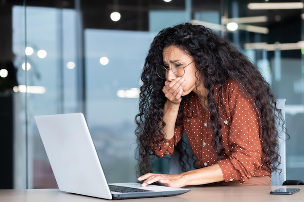 Businesswoman has severe nausea latin american woman at work sick working sitting at table with