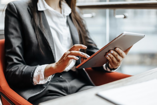 Businesswoman at her workplace reads information on a tablet A woman works with documents and searches for insights on the Internet The girl is thinking about the idea of a new startup in the office