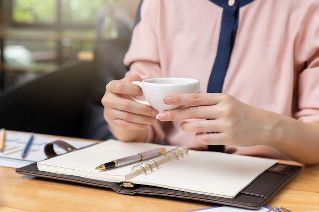 Businesswoman holding coffee cup and discussing sale analysis Chart in coffee shop