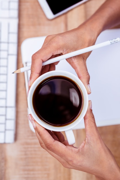 Foto tazza e penna di caffè della tenuta della donna di affari