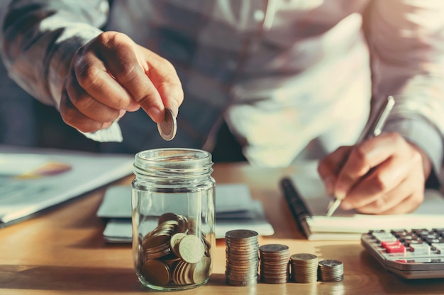 Businesswoman holding coins and putting in glass