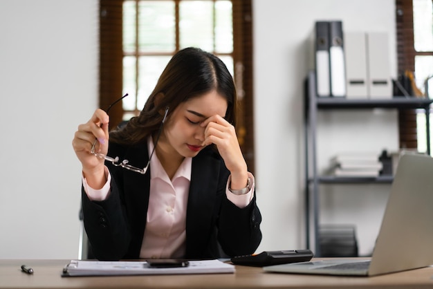 Photo businesswoman holding glasses and massaging her nose to relaxation after exhausted from overworked