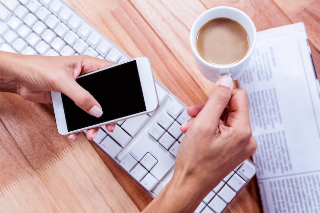 Businesswoman holding hot beverage and smartphone