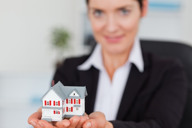 Businesswoman holding a miniature house