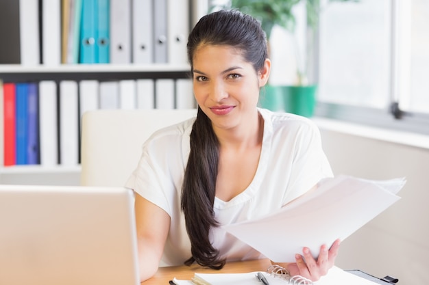 Businesswoman holding papers at office desk