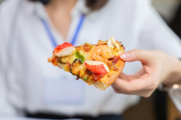 Photo businesswoman holding pizza snack on the desk office.