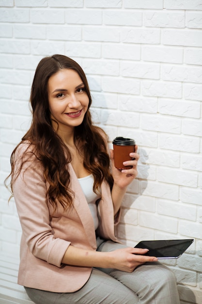 Businesswoman holding tablet and drinking coffee