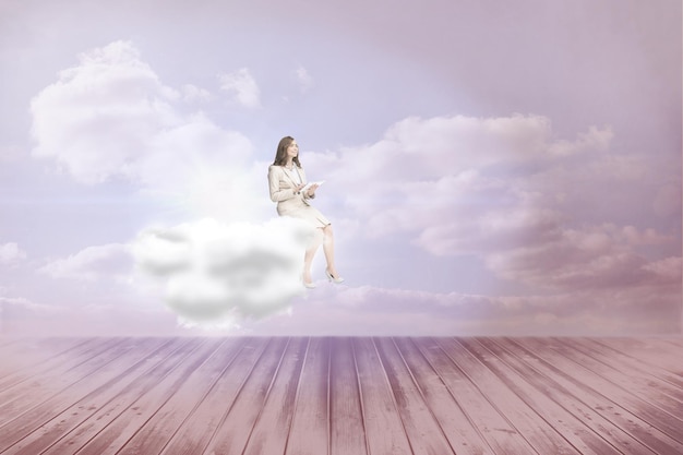 Businesswoman holding tablet and looking up against clouds in a room