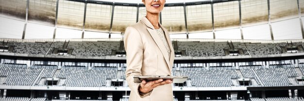 Businesswoman holding tablet pc against rugby goal post in a
stadium front view of rugby goal post in a empty stadium