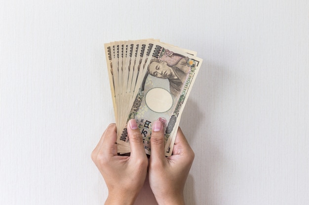 写真 白い背景、日本円で手持ちの1万円のお金を持つ実業家