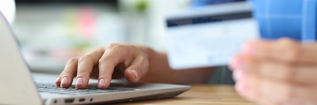 Photo businesswoman holds credit plastic card and dials number on laptop keyboard online payments via