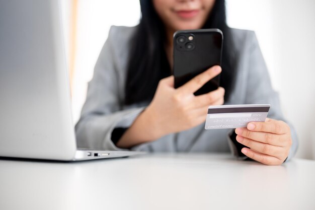 A businesswoman is holding a smartphone and a credit card using online payment banking