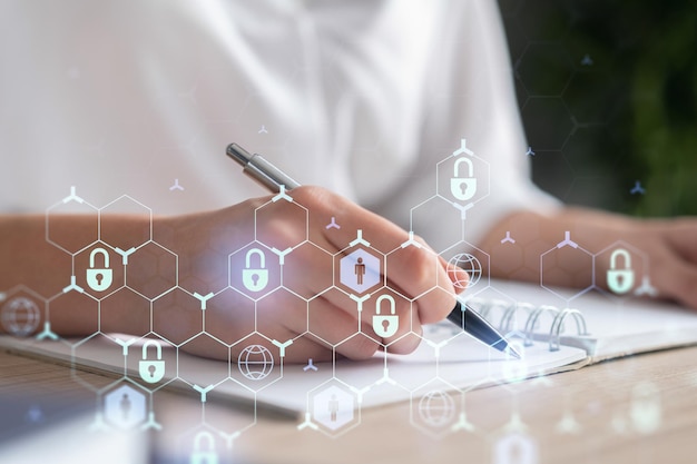 Businesswoman is taking notes of clients needs to protect cyber security from hacker attacks and save clients confidential data Padlock Hologram icons over the typing hands Formal wear