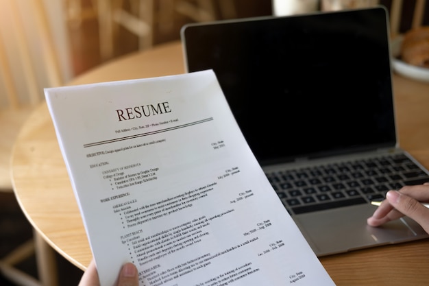 ビジネスマンまたは求職者がコーヒーショップで履歴書を再検討してから新しいものを見つける