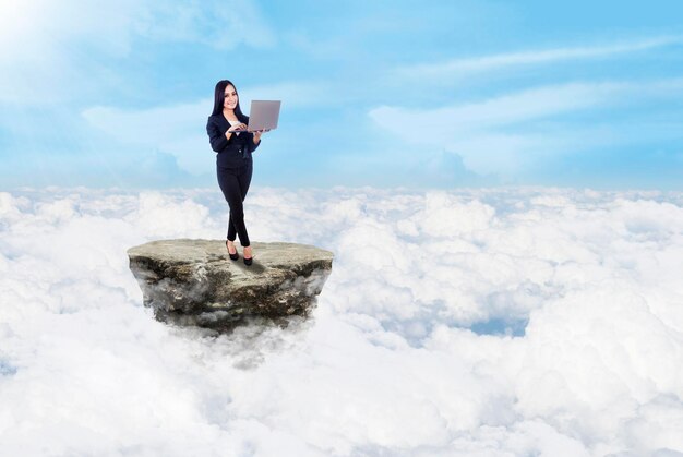 Businesswoman and laptop above clouds