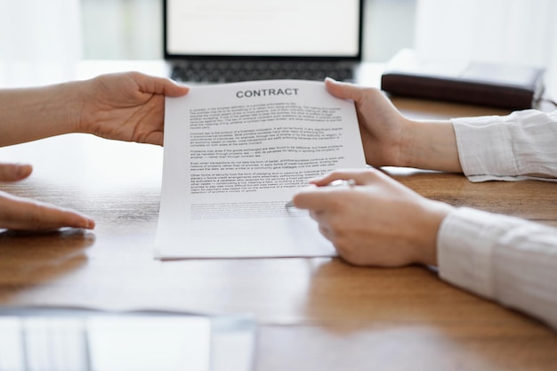 Businesswoman lawyer pointing into contract special points admitting something for colleague or client at the wooden desk in office. Business people teamwork and partnership, meeting concept.