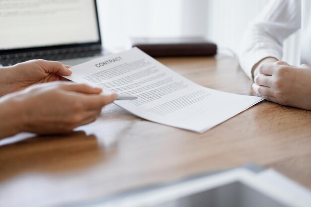 Businesswoman lawyer pointing into contract special points admitting something for colleague or client at the wooden desk in office. Business people teamwork and partnership, meeting concept.