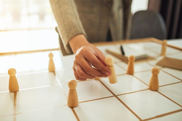 Businesswoman leader choosing wooden people from a group of employees on a planning board