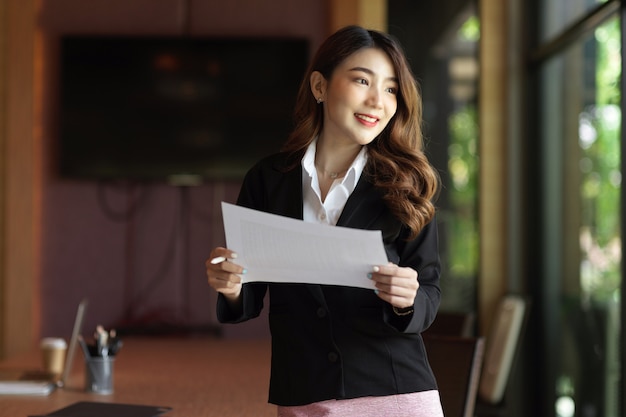 Businesswoman looking away through the window smiling thinking about business plan