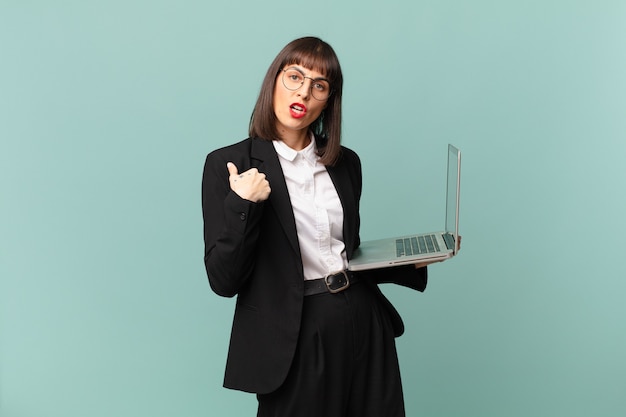 Businesswoman looking shocked and surprised with mouth wide open, pointing to self