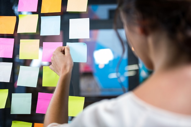 Photo businesswoman looking at sticky note