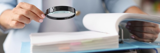 Businesswoman looking through magnifying glass tool on documents