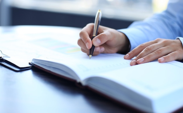 Businesswoman makes a note in notebook.