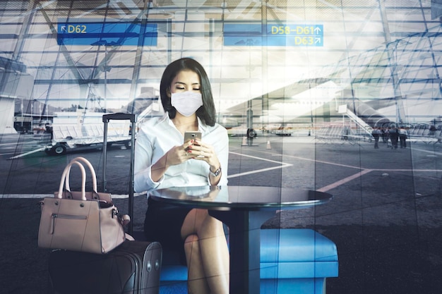 Businesswoman in mask sits with airport background