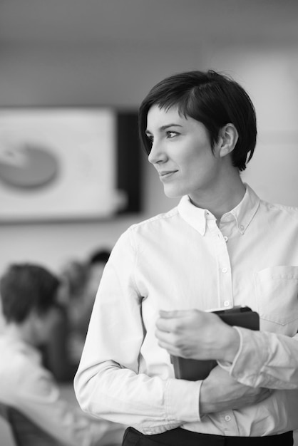 businesswoman on meeting using tablet computer  blured group of business people in background at  modern bright startup office interior