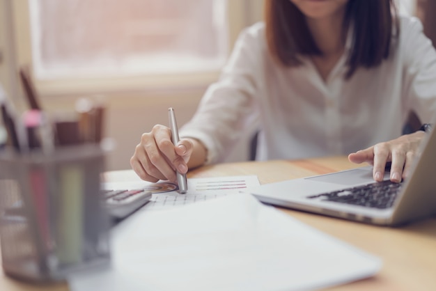 Businesswoman in office and use computer and calculator to perform financial accounting.