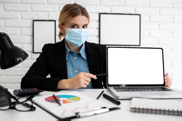 Businesswoman in the office with medical mask and laptop