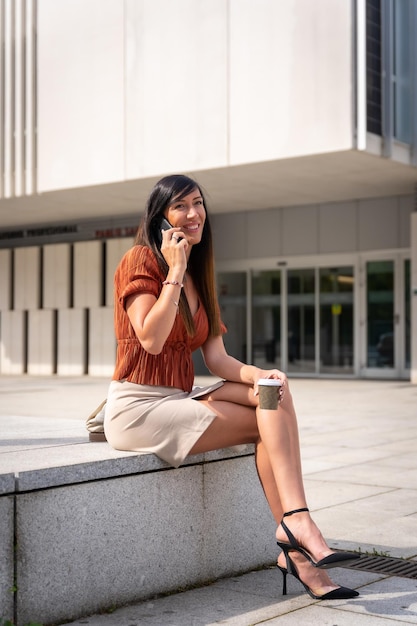 Businesswoman outside the office making a call with the phone