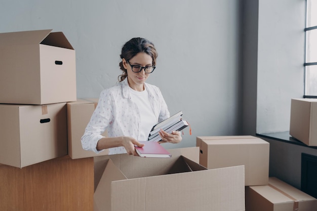 Businesswoman packs things in cardboard boxes on moving day preparing for relocation in new office