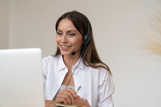 La donna di affari partecipa alle cuffie di usura di videoconferenza che comunicano con il cliente