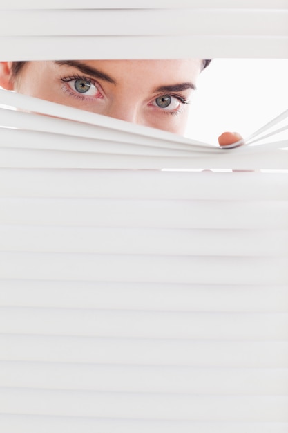 Businesswoman peeking through a venetian blind