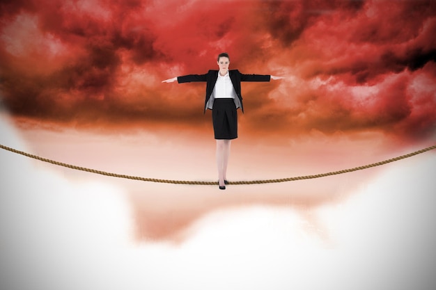 Foto donna di affari che esegue un atto di bilanciamento contro il fondo rosso del cielo nuvoloso
