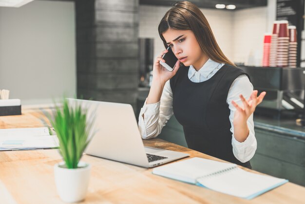 The businesswoman phones at the desktop