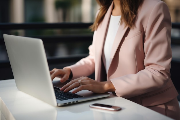 Businesswoman in pink blazer typing on laptop