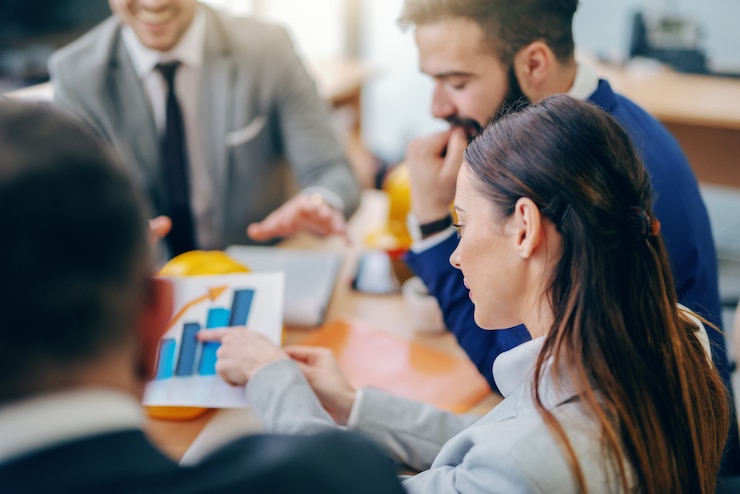 Photo businesswoman pointing at chart while sitting at meeting in boardroom. difficult things take a long time, impossible things a little longer.