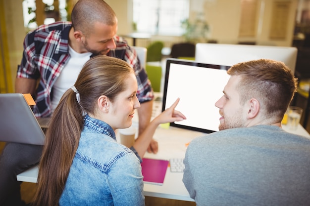 Businesswoman pointing on computer while discussing in office