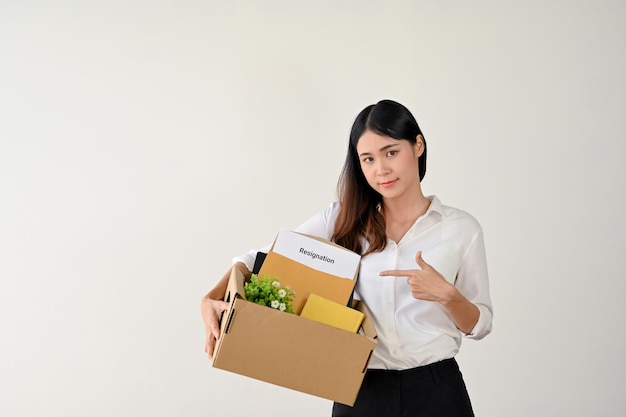 A businesswoman pointing her finger at her cardboard box with her resignation letter