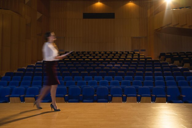 Деловая женщина практикует и учит сценарий во время ходьбы в аудитории