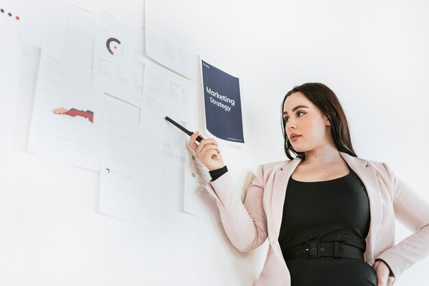 Businesswoman presenting a marketing strategy on a white wall