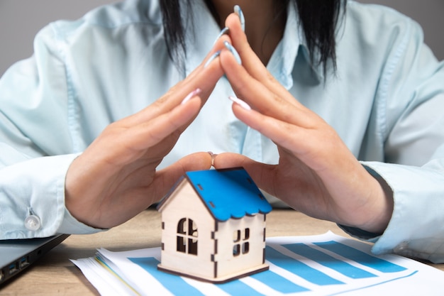 Businesswoman protects the house with her hands