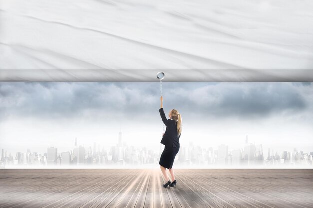 Businesswoman pulling a white screen against city on the horizon