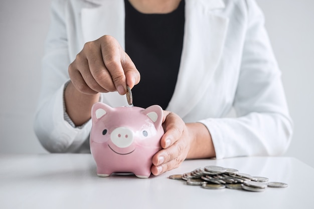 Photo businesswoman putting a coin into a piggy bank