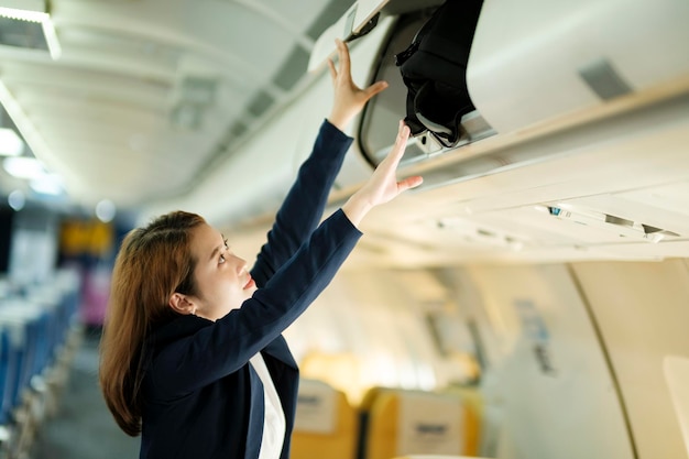 Businesswoman putting luggage on the top shelf on airplane