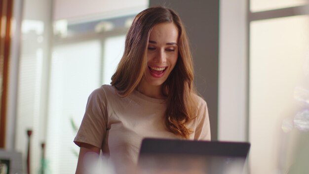 Businesswoman receiving good news on laptop Lady eating corn flakes on kitchen