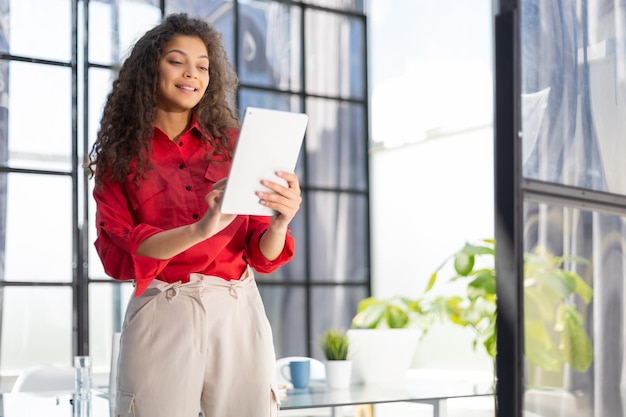 Businesswoman in red shirt standing in the office corridor with documents